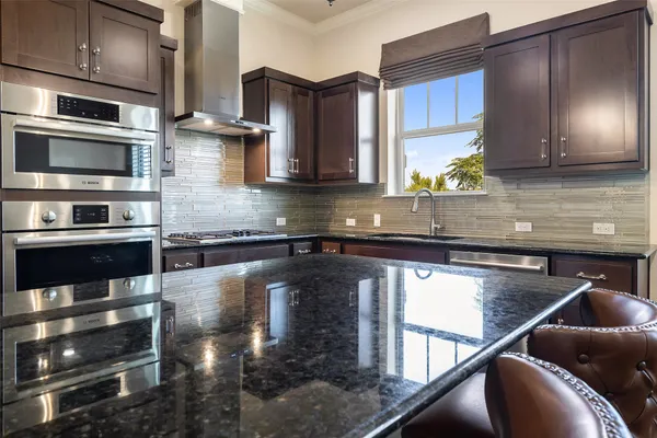 a kitchen with stainless steel appliances granite countertop a stove a sink and a microwave