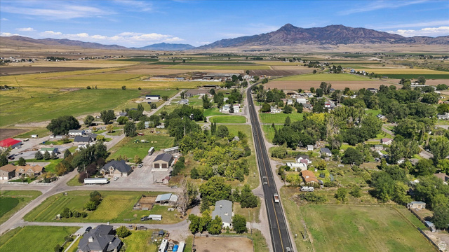 15295 North 5400th Street West Riverside, UT 84334 - Photo 50 of 54 Expansive rural landscape with a paved road, scattered residential structures, mature trees, and agricultural fields