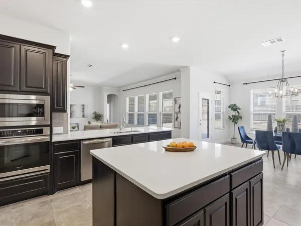 a kitchen with stainless steel appliances a stove a sink a kitchen island and chairs