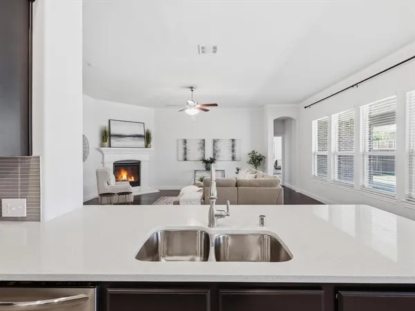 a kitchen with a sink and a refrigerator with white cabinets