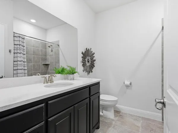 a bathroom with a granite countertop sink a toilet and a large mirror