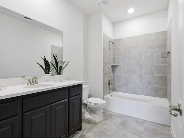 a bathroom with a bathtub shower sink mirror and toilet