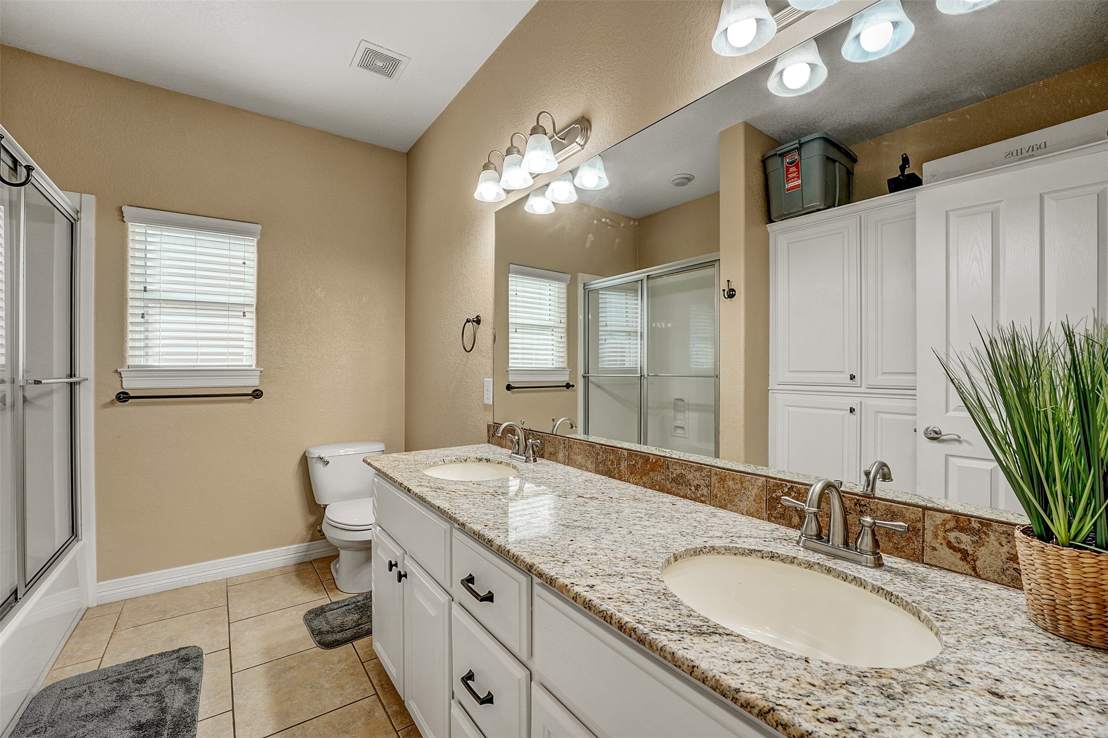 100 Magan Lane Jarrell, TX 76537 - Photo 25 of 32 a bathroom with a granite countertop double vanity sink a mirror and a shower