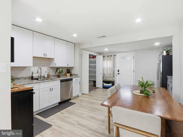 a kitchen with granite countertop stainless steel appliances a sink a stove a table and chairs