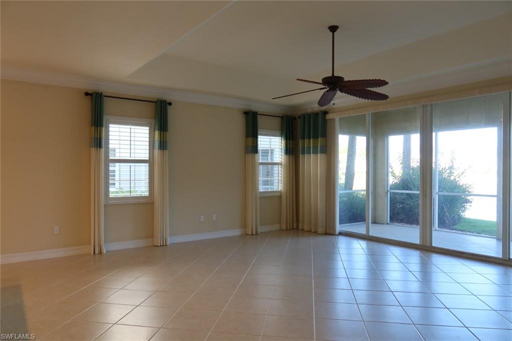 7168 Lemuria Circle, Unit 1701 Naples, FL 34109 - Photo 4 of 39 Spacious room featuring neutral tile flooring, a tray ceiling, and a ceiling fan