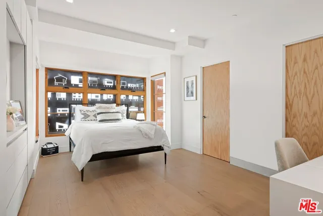 a bedroom with a bed a mirror and window