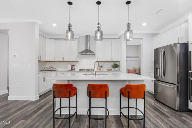 a kitchen with stainless steel appliances granite countertop a dining table chairs refrigerator and sink