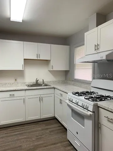 a kitchen with granite countertop cabinets stainless steel appliances and wooden floor