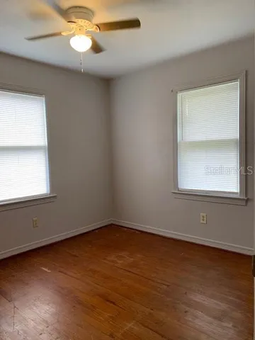 an empty room with wooden floor and windows