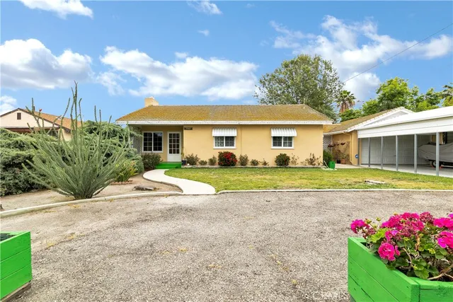 a view of a white house with a big yard and potted plants
