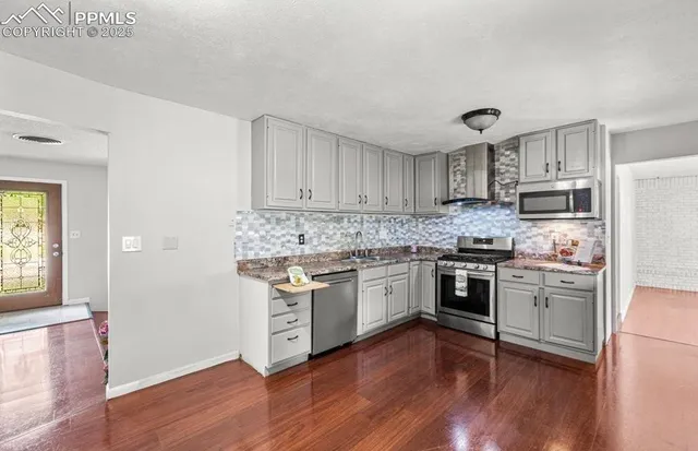 a kitchen with granite countertop wooden floors and white stainless steel appliances