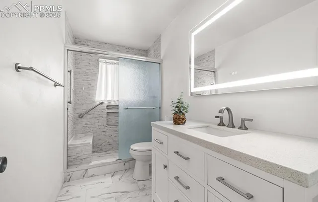 a bathroom with a granite countertop sink a toilet and a shower