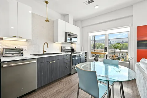 a kitchen with stainless steel appliances granite countertop a kitchen island hardwood floor sink stove dining table and chairs