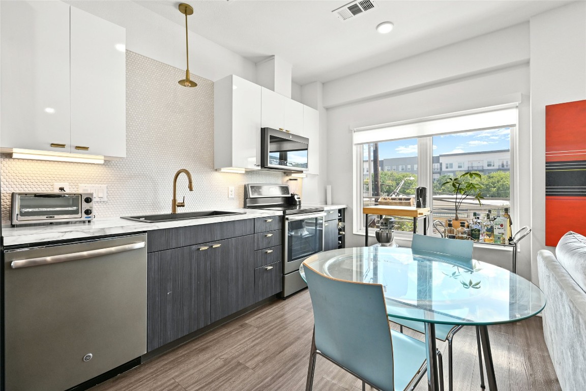 4361 South Congress Avenue, Unit 228 Austin, TX 78745 - Photo 5 of 20 a kitchen with stainless steel appliances granite countertop a kitchen island hardwood floor sink stove dining table and chairs