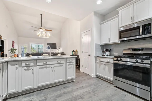 a kitchen with stainless steel appliances granite countertop a stove a sink and a microwave