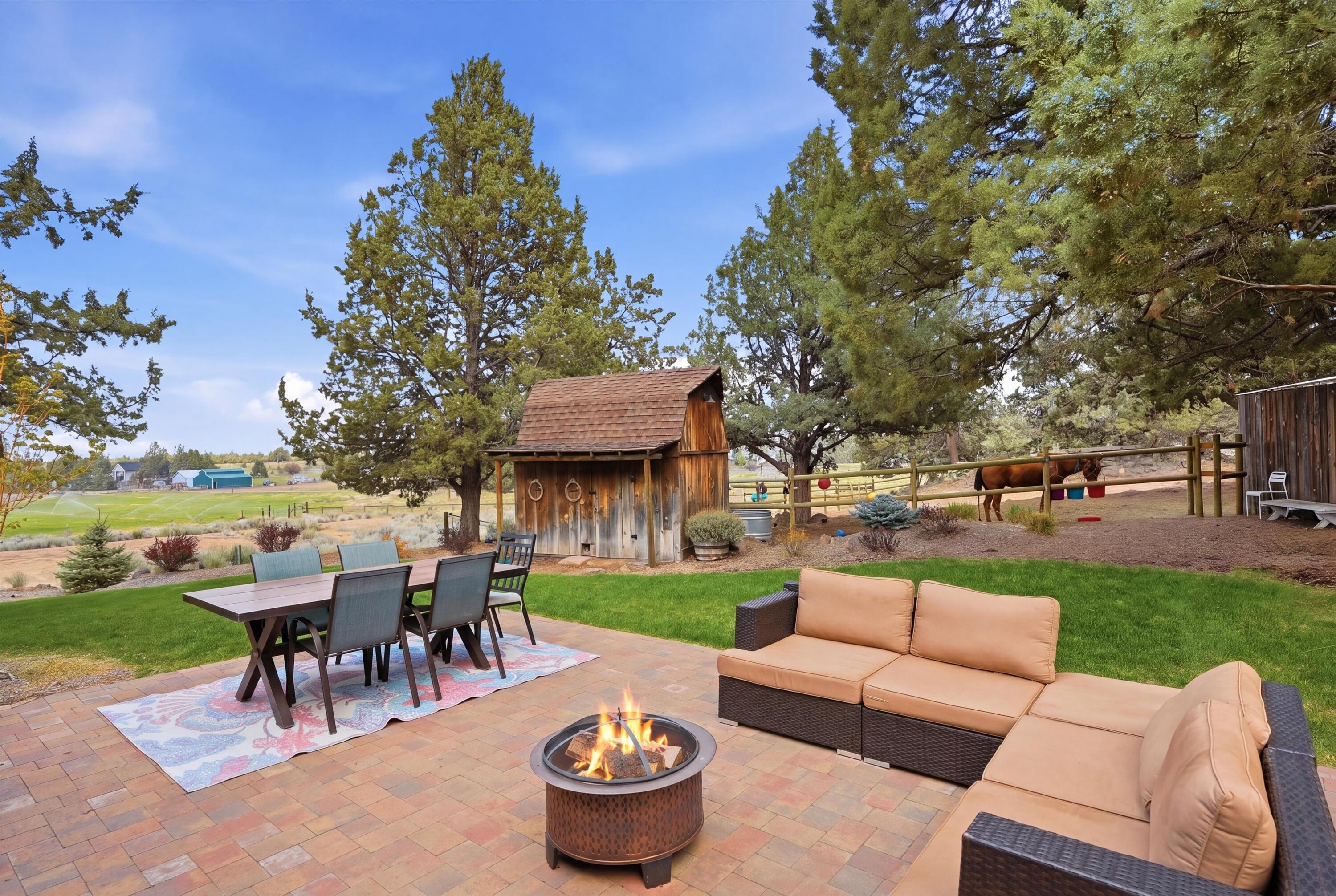 61280 Larsen Road Bend, OR 97702 - Photo 27 of 58 a view of a patio with couches and a table and chairs with plants and trees
