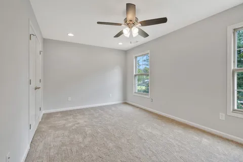 an empty room with windows and fan