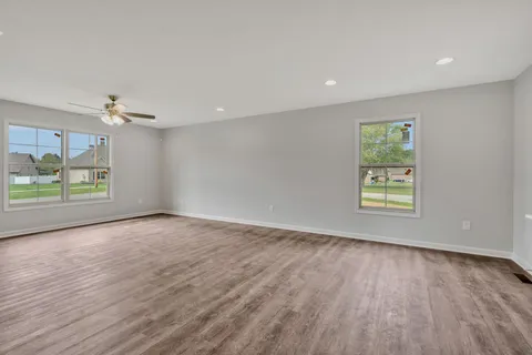 a view of an empty room with a window and wooden floor