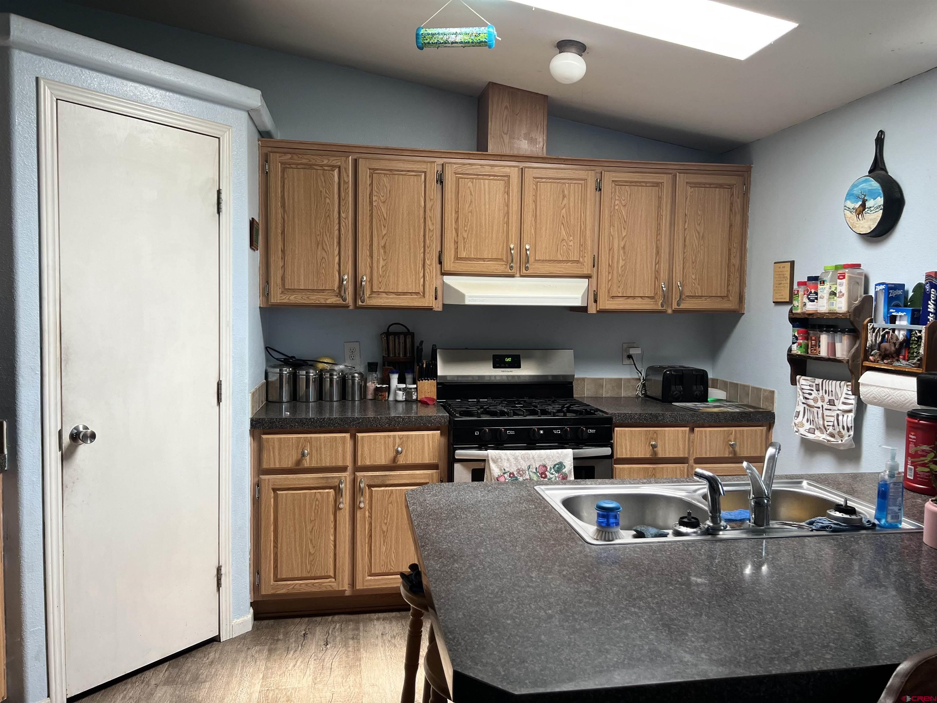 21296 H75 Road Delta, CO 81416 - Photo 10 of 25 a kitchen with stainless steel appliances granite countertop a stove a sink a refrigerator white cabinets and wooden floor