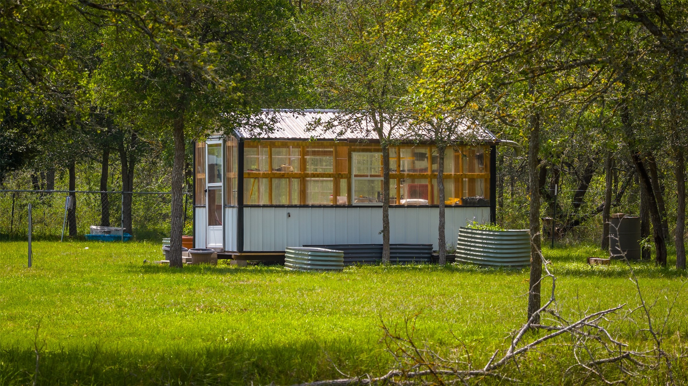 4082 Old Colony Line Road Lockhart, TX 78644 - Photo 39 of 40 A charming sunroom with a metal roof and glass panels sits nestled among verdant trees.