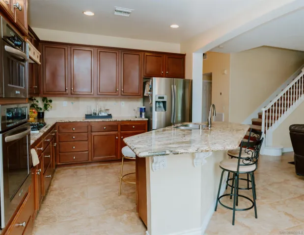 a kitchen with stainless steel appliances kitchen island granite countertop a sink refrigerator and cabinets
