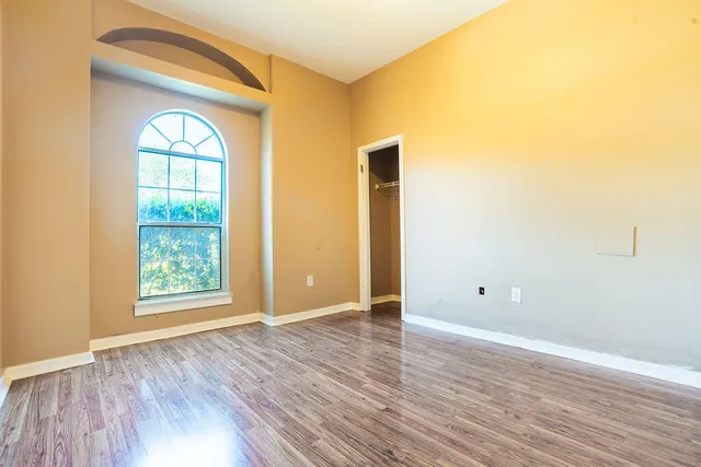 an empty room with wooden floor and windows