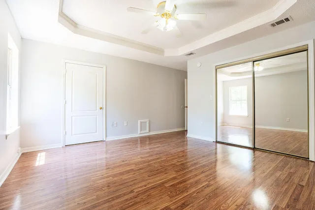 an empty room with wooden floor and a ceiling fan