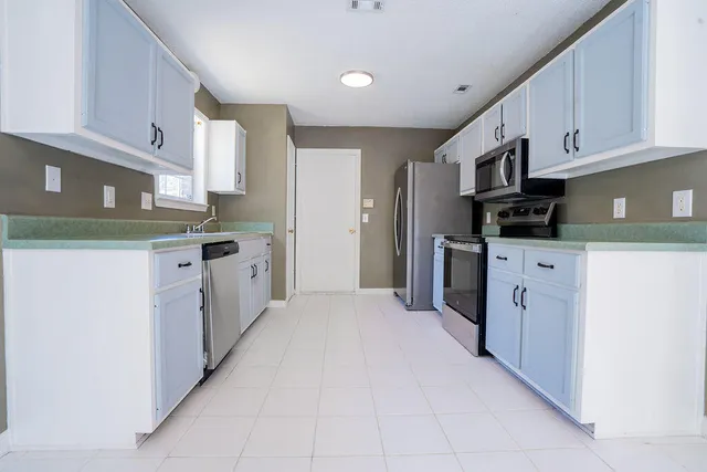 a kitchen with stainless steel appliances granite countertop a refrigerator oven a sink dishwasher and white cabinets with wooden floor