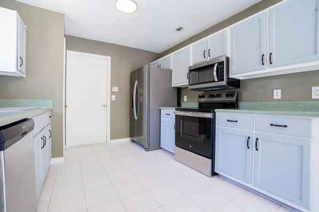 a kitchen with stainless steel appliances a refrigerator stove and white cabinets