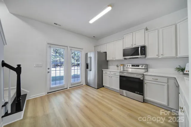 a kitchen with stainless steel appliances a stove top oven a sink dishwasher a refrigerator and a microwave