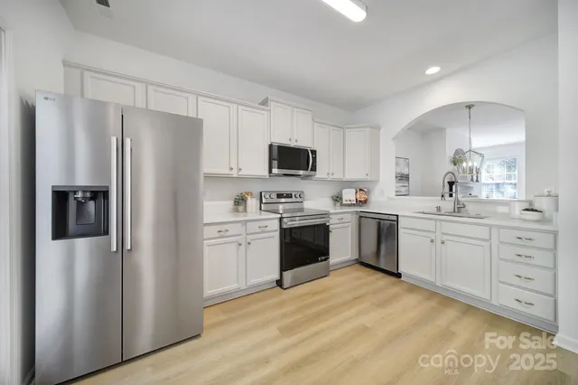 a kitchen with white cabinets stainless steel appliances and a refrigerator
