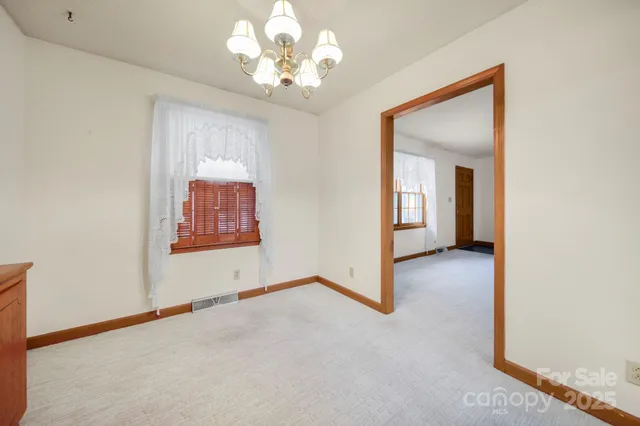 an empty room with chandelier fan and windows