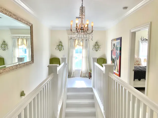 a view of a hallway to a livingroom with wooden floor and stairs