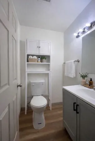 a view of a hallway with wooden floor and a bathroom