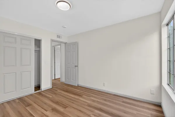 a view of empty room with wooden floor and fan