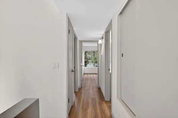 a view of a hallway with wooden floor and a bathroom