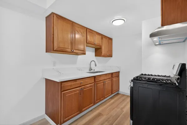 a kitchen with granite countertop cabinets a sink and wooden floor