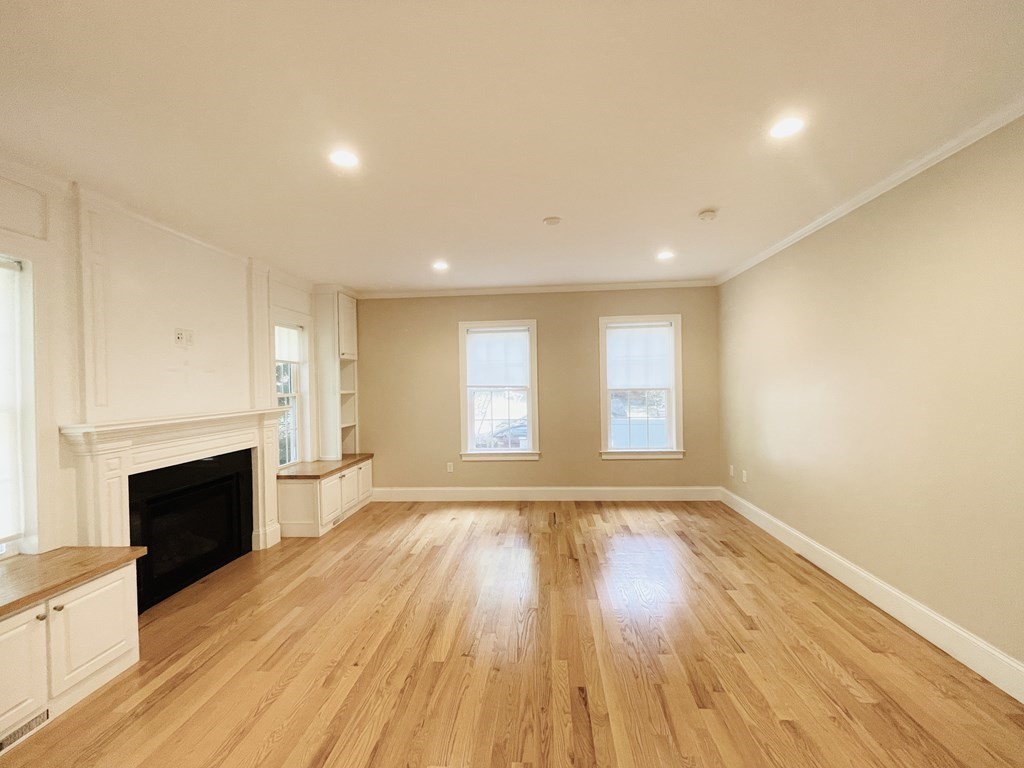 127 Lowell Street Lexington, MA 02420 - Photo 7 of 33 an empty room with wooden floor and fireplace
