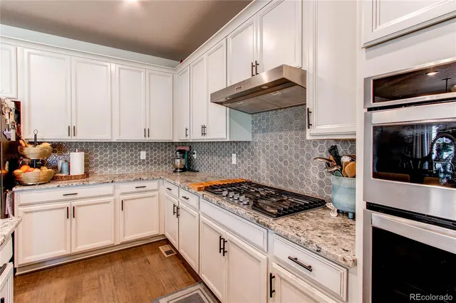 a kitchen with granite countertop white cabinets and white appliances