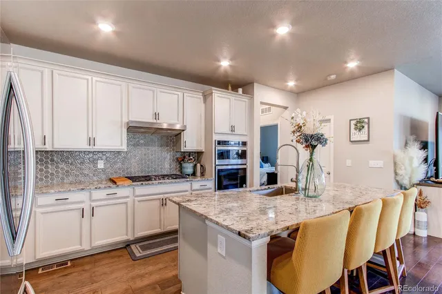 a kitchen with granite countertop white cabinets and stainless steel appliances