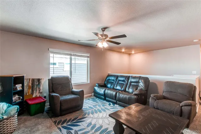 a living room with furniture ceiling fan and a window
