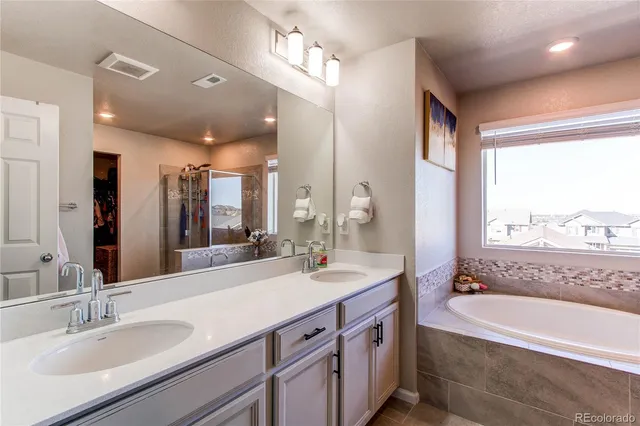 a bathroom with a tub double sink window and mirror
