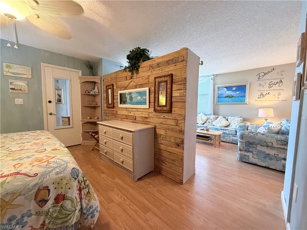 5800 Bonita Beach Road Southwest, Unit 2805 Bonita Springs, FL 34134 - Photo 11 of 30 Bedroom featuring a textured ceiling, a ceiling fan, and light wood-style flooring