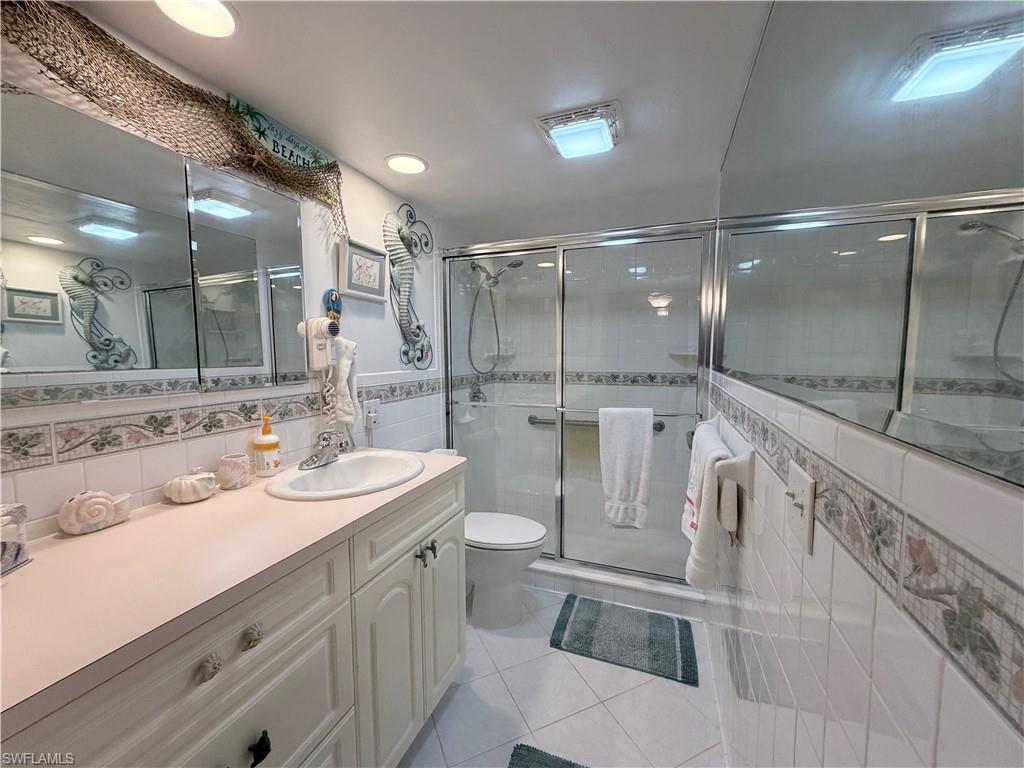 5800 Bonita Beach Road Southwest, Unit 2805 Bonita Springs, FL 34134 - Photo 14 of 30 Full bath featuring light tile patterned floors, vanity, a shower stall, and tile walls