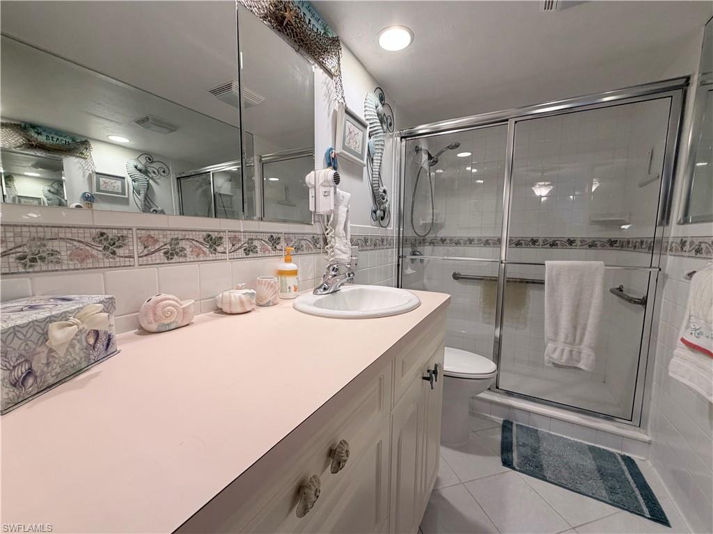 5800 Bonita Beach Road Southwest, Unit 2805 Bonita Springs, FL 34134 - Photo 16 of 30 Bathroom featuring vanity, a shower stall, tile walls, light tile patterned floors, and backsplash