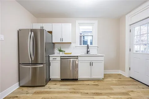 a kitchen with white cabinets stainless steel appliances and window