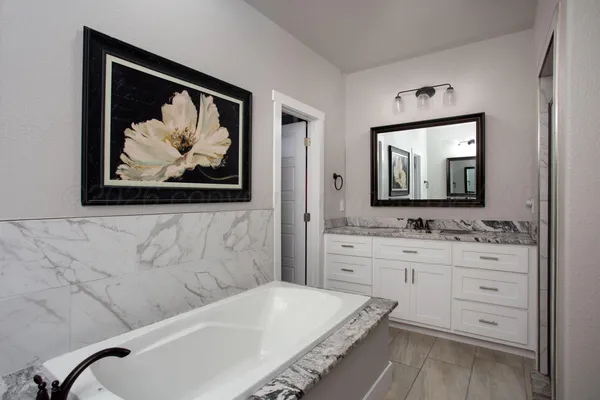 a bathroom with a tub a sink and mirror