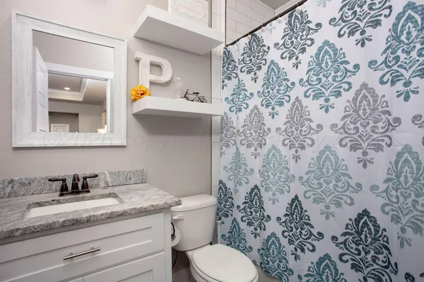 a bathroom with a granite countertop sink and a toilet