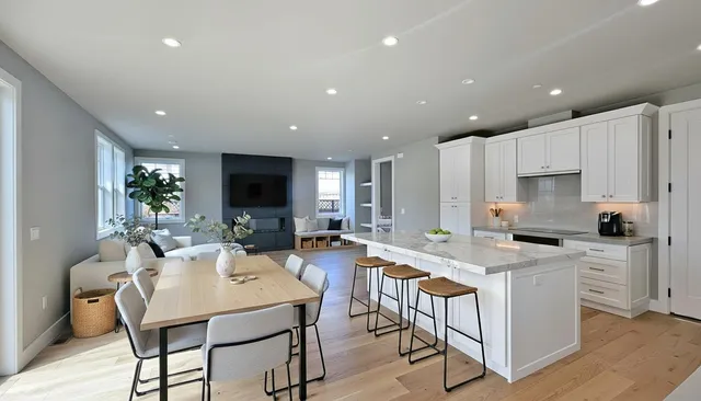 a kitchen with stainless steel appliances kitchen island granite countertop a stove a sink a refrigerator and a dining table with wooden floor