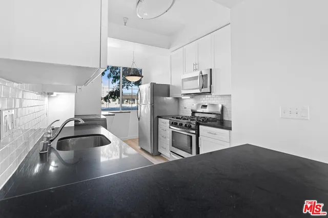 a kitchen with granite countertop a sink and stainless steel appliances